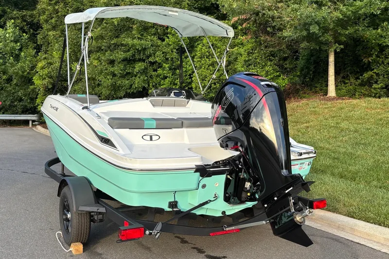 Slide: The Image of 2027 Tahoe T18 boat with outboard motor on trailer, parked near greenery. - 4