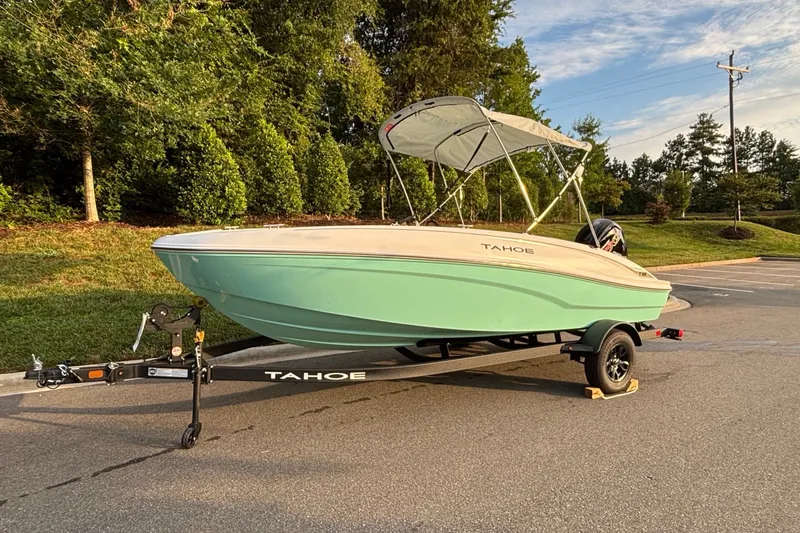 Slide: The Image of 2027 Tahoe T18 boat on trailer, parked outdoors with lush greenery background. - 1