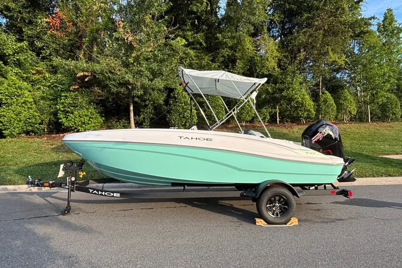 The Image of 2027 Tahoe T18 boat on trailer, parked on street with green trees in background. - 0