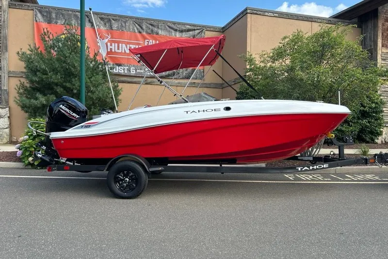 The Image of 2027 Tahoe T18 boat with red hull and canopy on trailer, parked outdoors. - 0