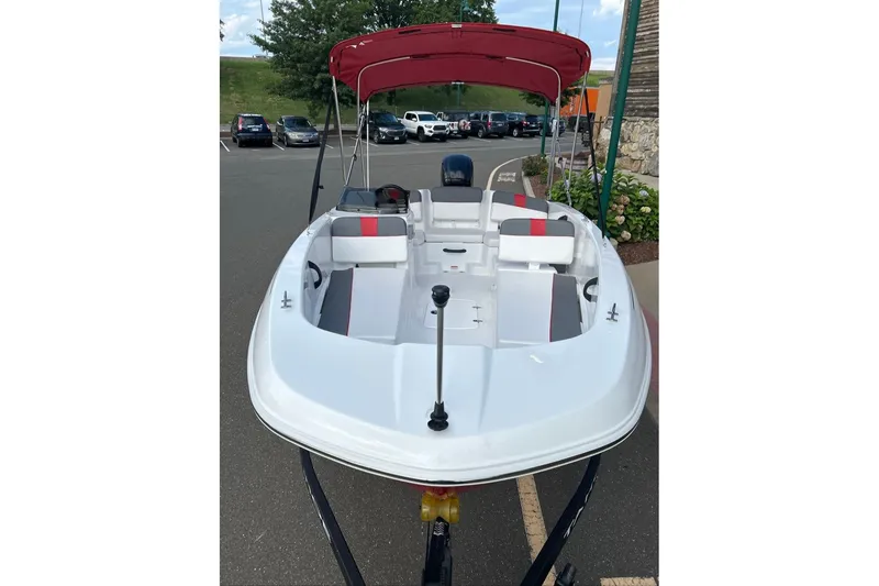 Slide: The Image of 2027 Tahoe T18 boat with red canopy, parked in a lot, showcasing sleek design and seating. - 2