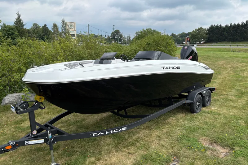 Slide: The Image of 2027 Tahoe T21 boat on trailer, parked on grassy area under cloudy sky. - 1