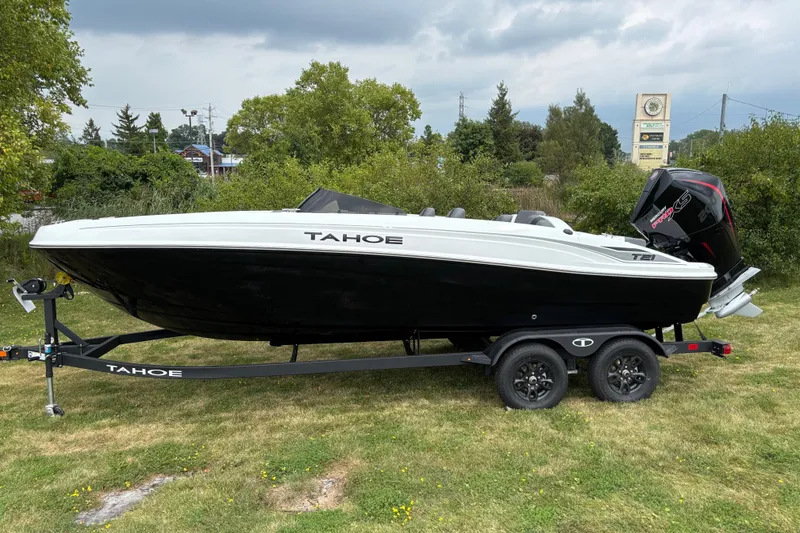 The Image of 2027 Tahoe T21 boat on trailer, black and white design, parked on grass. - 0