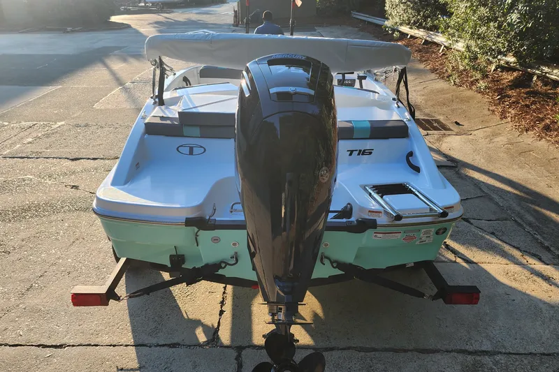 Slide: The Image of 2027 Tahoe T16 boat with outboard motor on a trailer, parked on a sunlit driveway. - 6