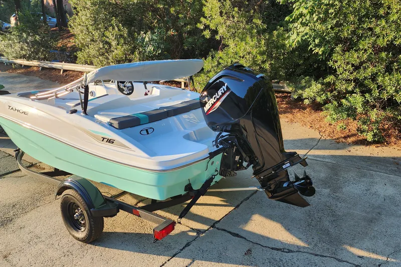 Slide: The Image of 2027 Tahoe T16 boat with Mercury outboard motor on trailer, parked outdoors. - 1