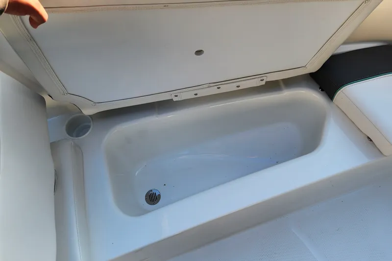 Slide: The Image of Open storage compartment in 2027 Tahoe T16 boat, featuring white interior and drain. - 65