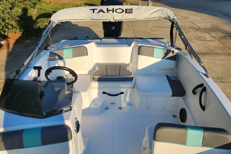 Slide: The Image of 2027 Tahoe T16 boat interior with seating, steering wheel, and canopy in sunlight. - 2
