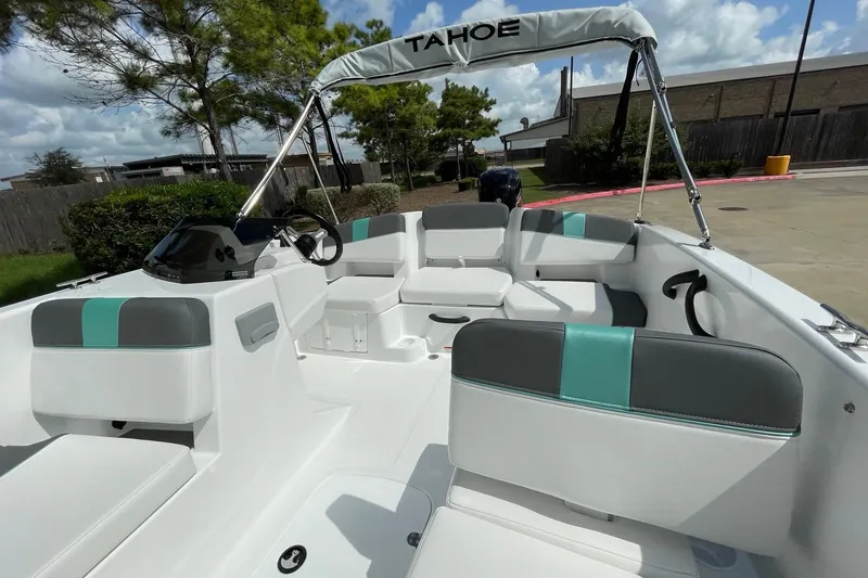 Slide: The Image of 2027 Tahoe T18 boat interior with modern seating and steering, parked outdoors. - 9
