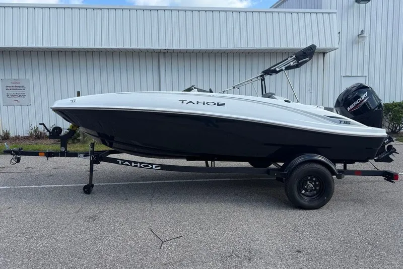 Slide: The Image of 2027 Tahoe T16 boat on trailer, white and black design, parked outdoors. - 2
