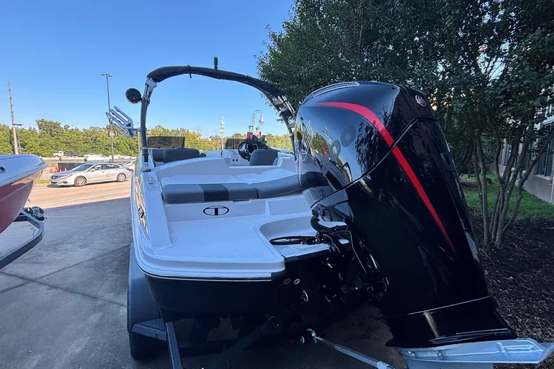 Slide: The Image of 2027 Tahoe T21 boat with powerful outboard motor, parked outdoors on a sunny day. - 2