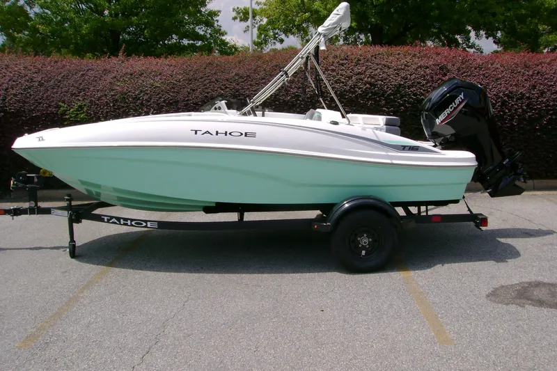 The Image of 2027 Tahoe T16 boat on trailer, parked outdoors with lush greenery background. - 0