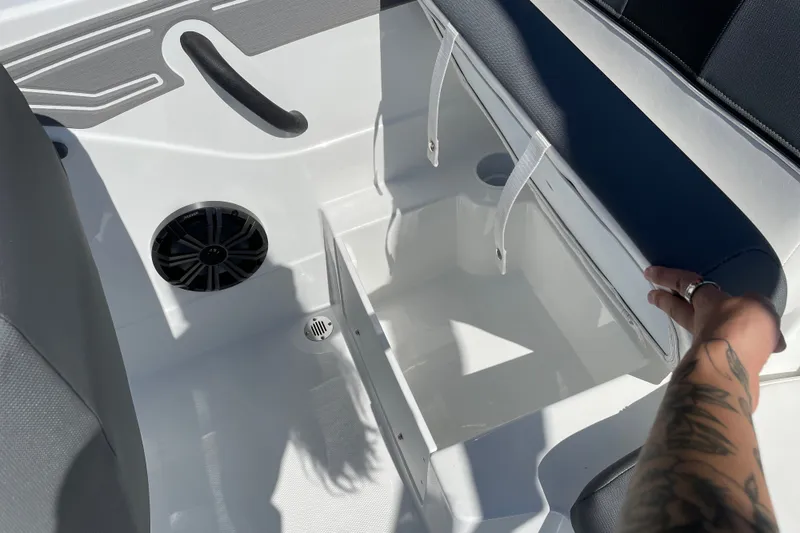Slide: The Image of Open storage compartment in 2027 Tahoe T21 boat, featuring speaker and seating area. - 16