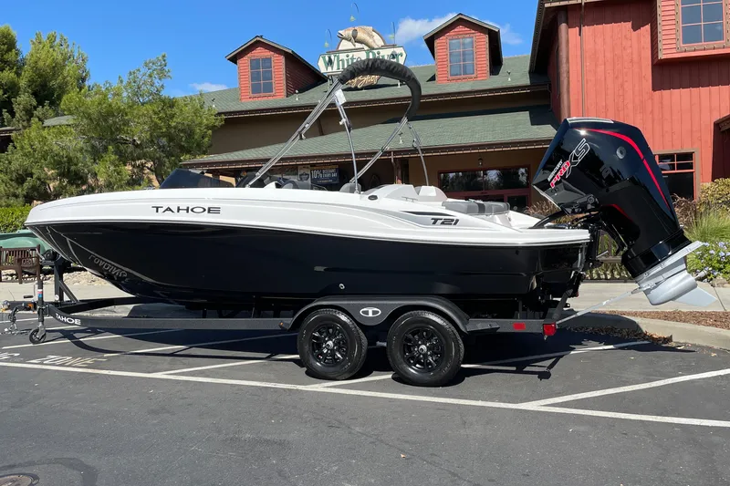 Slide: The Image of 2027 Tahoe T21 boat on trailer, parked outdoors near rustic building. - 3