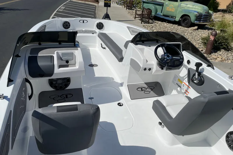 Slide: The Image of 2027 Tahoe T21 boat interior with modern seating and steering, parked near a vintage truck. - 6