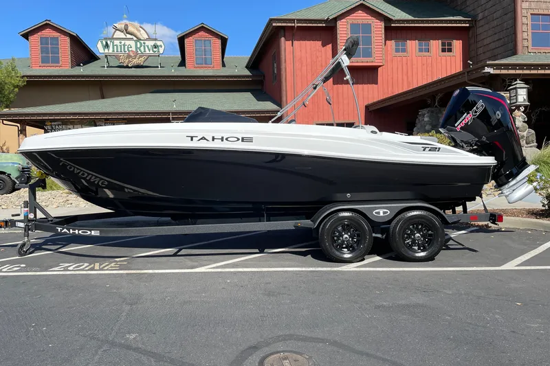Slide: The Image of 2027 Tahoe T21 boat on trailer, parked outside a rustic building. - 1
