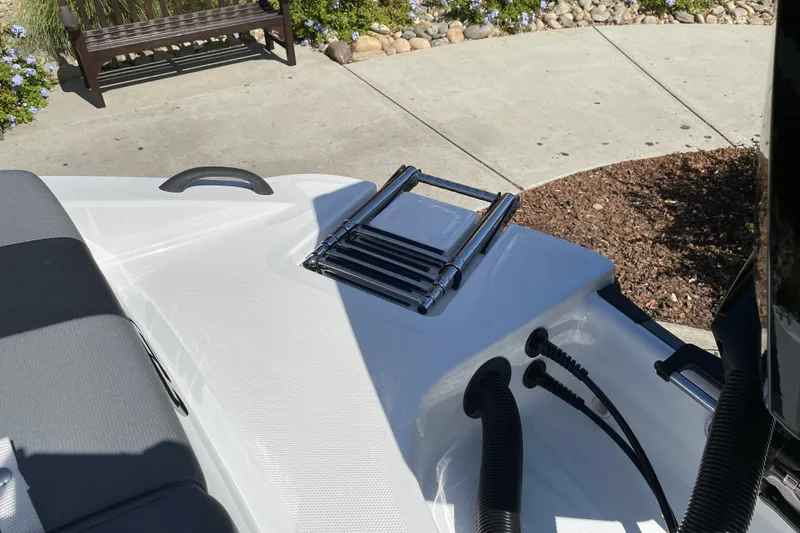Slide: The Image of Tahoe T21 2027 boat with foldable ladder and seating, parked on concrete near garden. - 30