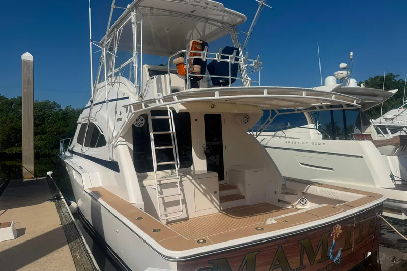 Slide: The Image of 2003 Bertram 450 Convertible yacht docked, showcasing spacious deck and sleek design. - 2