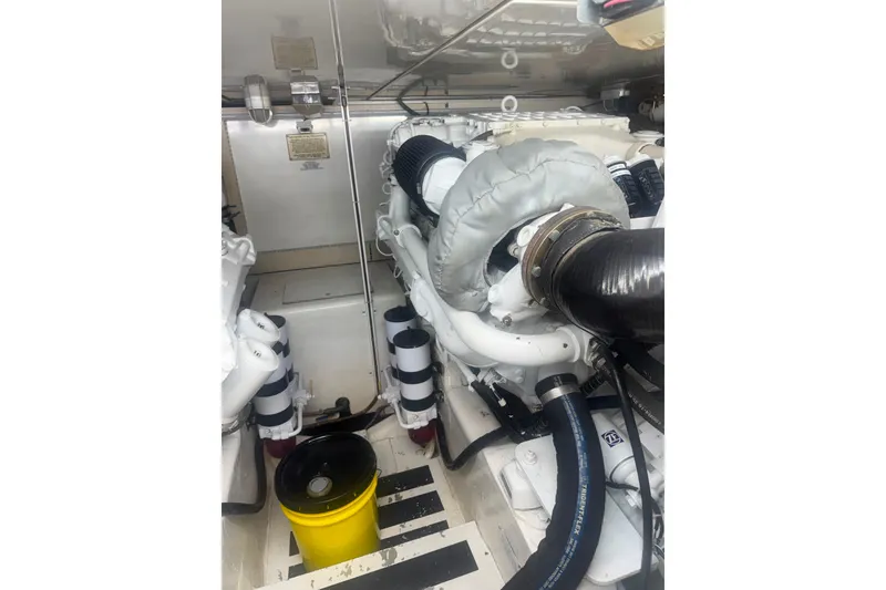 Slide: The Image of Engine room of a 2003 Bertram 450 Convertible yacht, featuring mechanical components and a yellow bucket. - 24