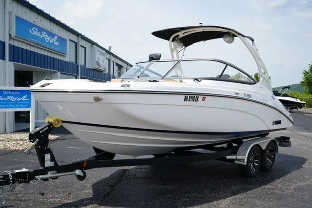 Slide: The Image of 2022 Yamaha 212 boat on trailer outside dealership, sunny day. - 2