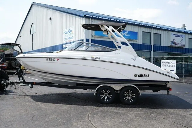 The Image of 2022 Yamaha 212 boat on trailer outside showroom, featuring sleek white design. - 1