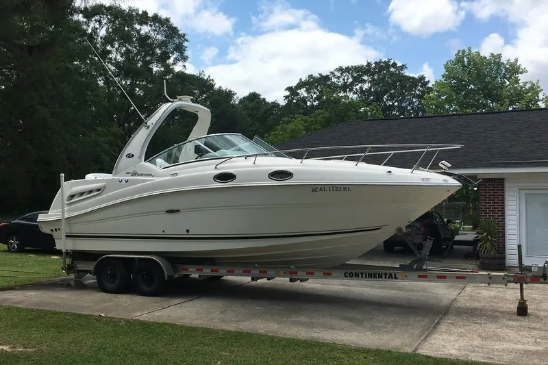 Slide: The Image of 2007 Sea Ray Sundancer 260 boat on trailer, parked in driveway, surrounded by trees. - 2