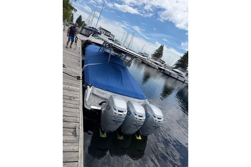 Slide: The Image of 2022 Nor-Tech 340 Sport boat docked with triple outboard engines, covered in blue tarp. - 33