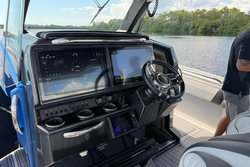 Slide: The Image of 2020 Nor-Tech boat cockpit with advanced navigation screens and steering wheel on a calm waterway. - 17