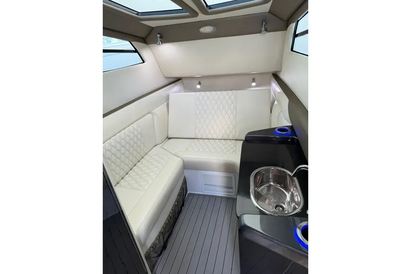 Slide: The Image of Luxurious 2020 Nor-Tech boat interior with white quilted seating and compact kitchenette. - 28