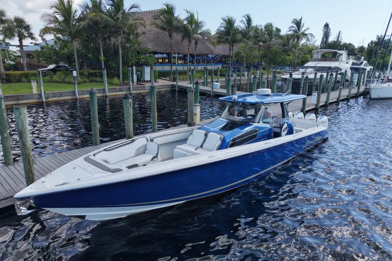 The Image of 2020 Nor-Tech boat docked by palm trees, featuring sleek blue and white design. - 1