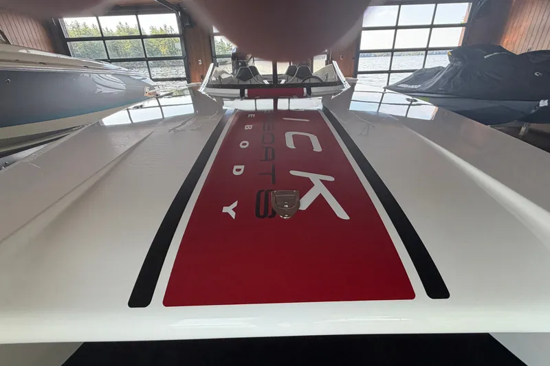 Slide: The Image of 2024 Trick 23 Widebody boat in showroom, showcasing sleek design and red detailing. - 20