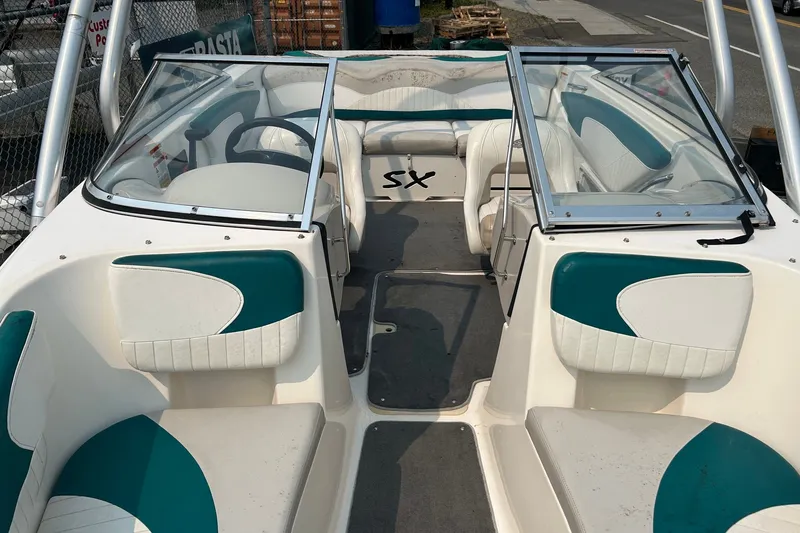 Slide: The Image of 2006 Glastron SX 195 boat interior with teal and white seating, open windshield. - 10