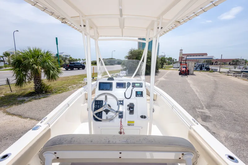 Slide: The Image of 2016 Cobia 201 Center Console boat with steering wheel and controls, parked near a road. - 23