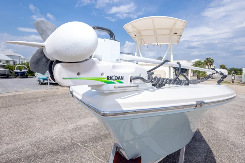 Slide: The Image of 2016 Cobia 201 Center Console boat with trolling motor, parked outdoors under a blue sky. - 18