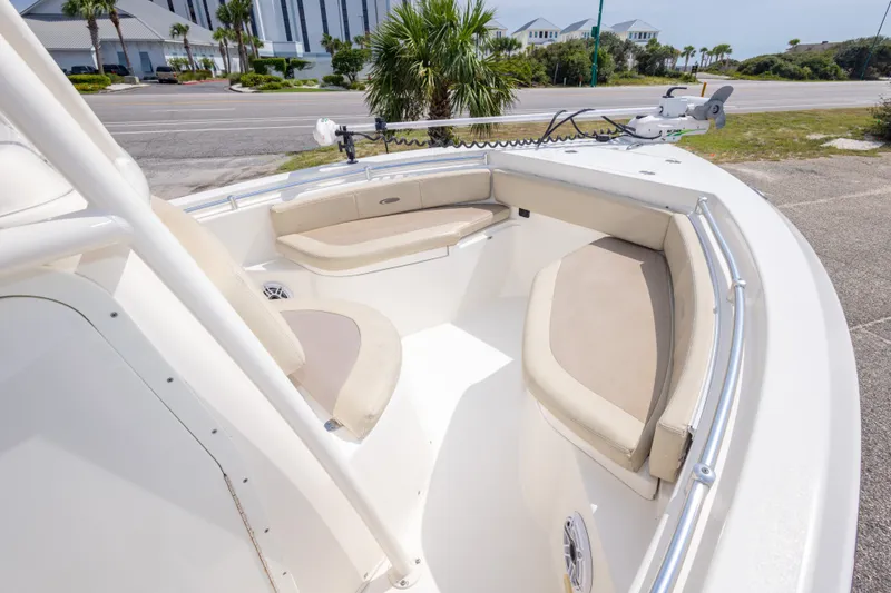 Slide: The Image of 2016 Cobia 201 Center Console boat with beige seating and trolling motor, parked near a road. - 29