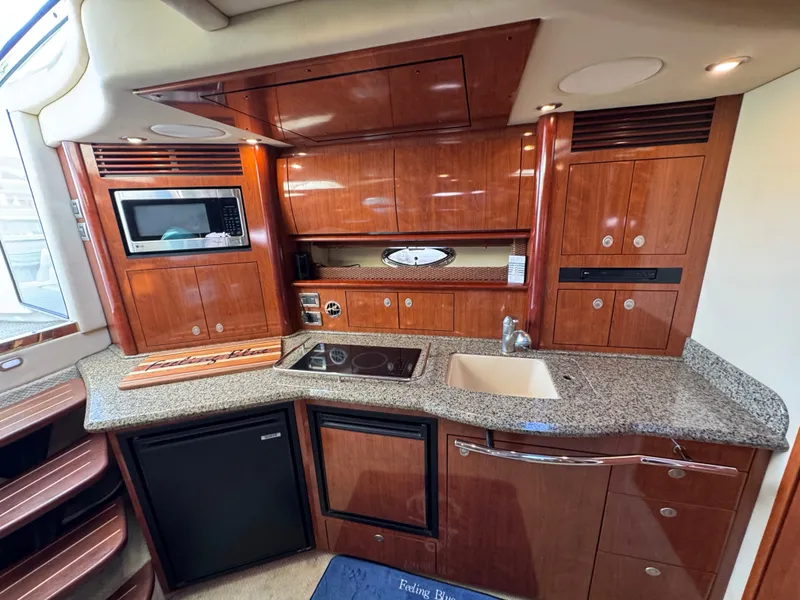 Slide: The Image of The 2005 Sea Ray 390 Sundancer's galley features elegant wood cabinets, a sink, and modern appliances. - 41