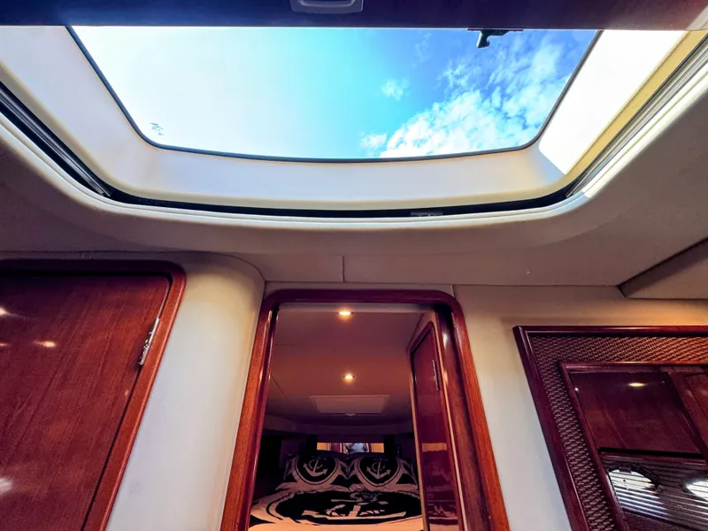 Slide: The Image of Interior of the Sea Ray 390 Sundancer with skylights and wooden doors, revealing a cozy sleeping area. - 49