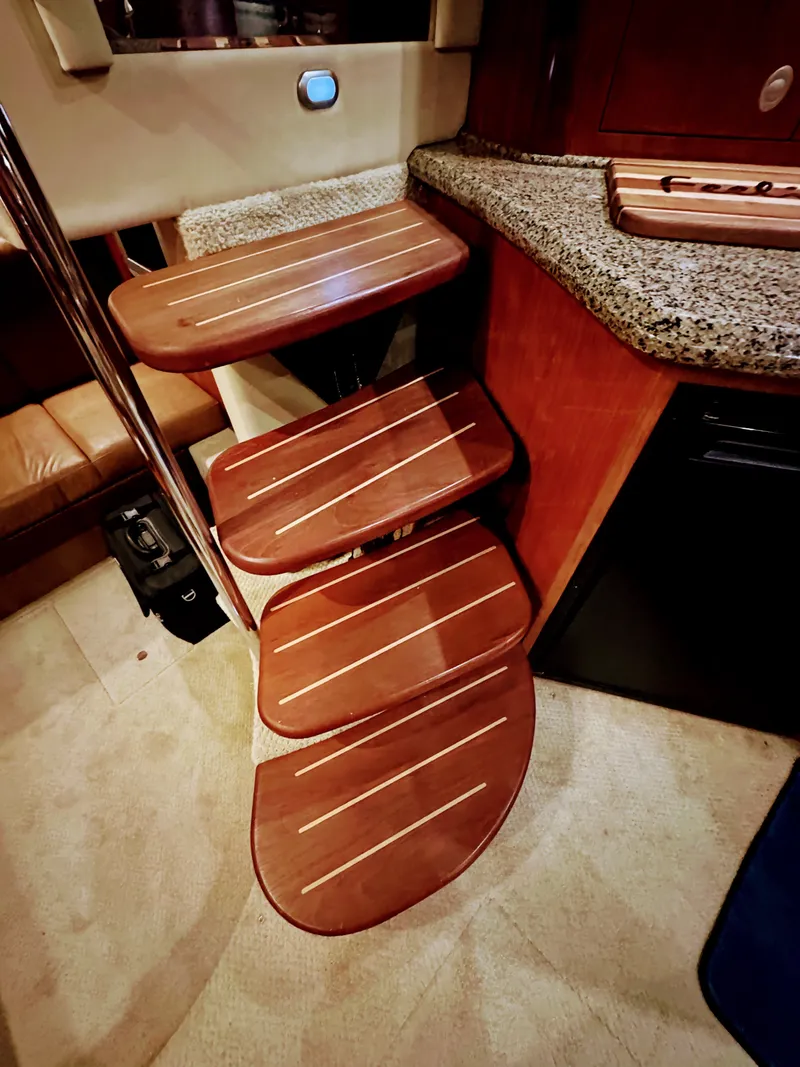 Slide: The Image of Wooden staircase with four steps in a boat cabin, next to a countertop and refrigerator. - 43