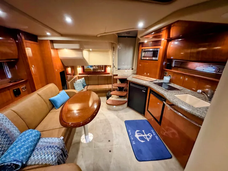 Slide: The Image of The 2005 Sea Ray 390 Sundancer interior features a cozy seating area, kitchenette, and wood paneling. - 38
