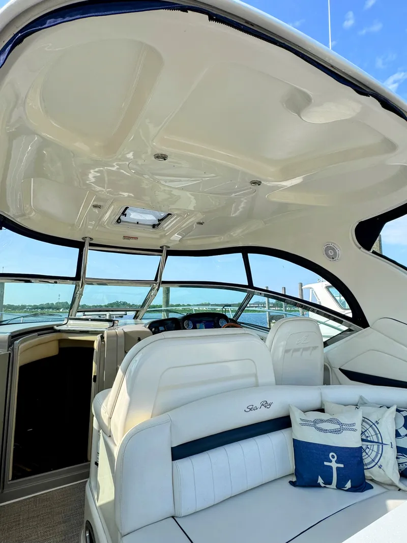 Slide: The Image of The image shows the cockpit of a 2005 Sea Ray 390 Sundancer with white seating and blue cushions. - 27