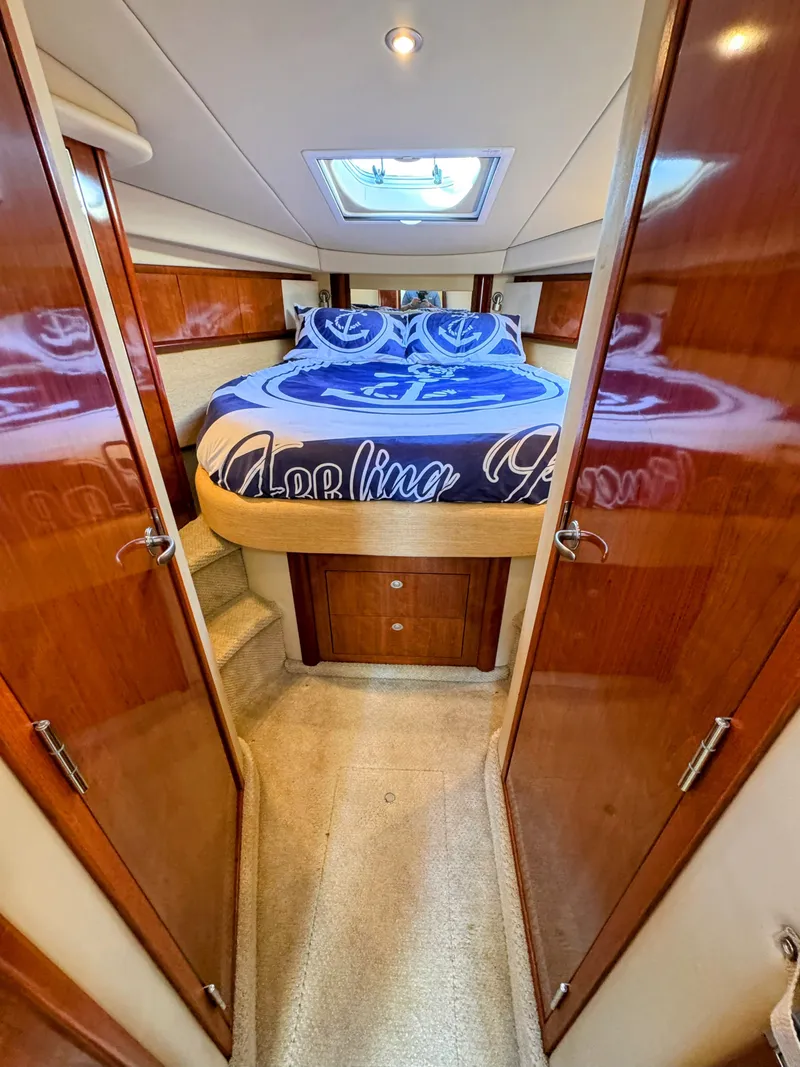 Slide: The Image of The cabin of the 2005 Sea Ray 390 Sundancer features a cozy bed with blue bedding. - 46