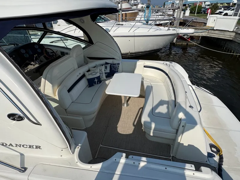 Slide: The Image of The image shows the cockpit of a 2005 Sea Ray 390 Sundancer with white seating and a table. - 19