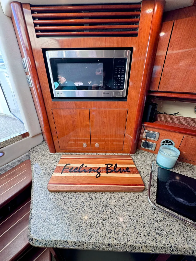 Slide: The Image of The 2005 Sea Ray 390 Sundancer's galley features a microwave and countertop with a cutting board. - 42
