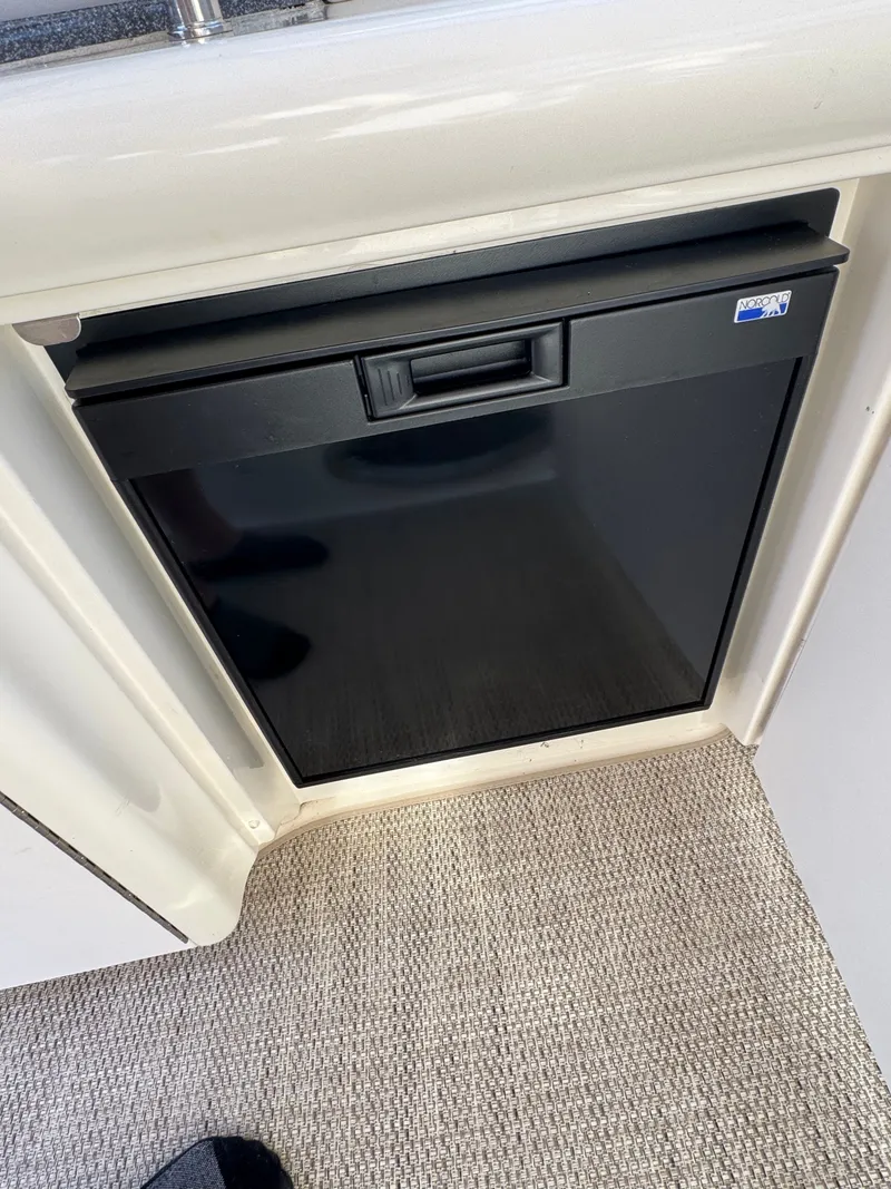 Slide: The Image of A small black refrigerator is integrated into the white interior paneling of a boat. - 25