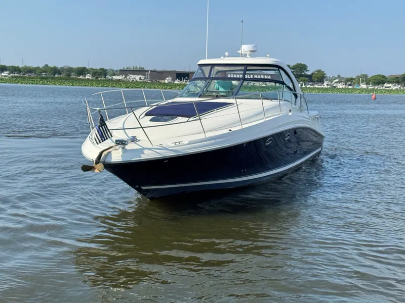 Slide: The Image of A 2005 Sea Ray 390 Sundancer cruising on calm water. It features a sleek design and white cabin. - 2