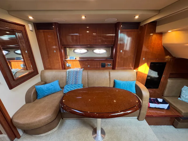 Slide: The Image of The cabin of the 2005 Sea Ray 390 Sundancer features an elegant seating area with a glossy wooden table. - 40