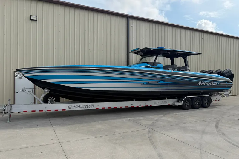 Slide: The Image of 2027 Nor-Tech boat on trailer, blue and black design, parked outside a warehouse. - 37
