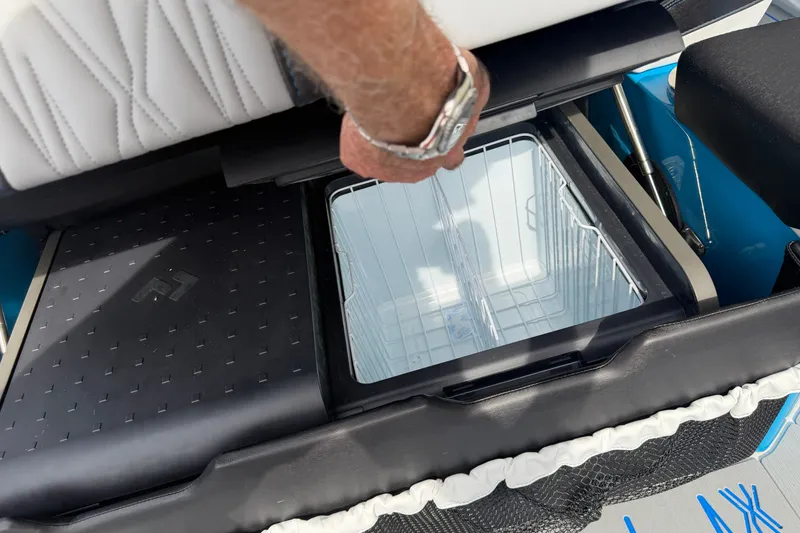 Slide: The Image of Man opening storage compartment on 2027 Nor-Tech boat with white seating. - 17