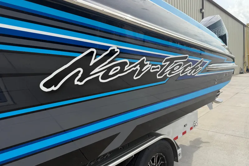 Slide: The Image of 2027 Nor-Tech boat with blue and black stripes, parked outside a building. - 38