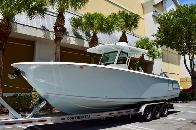 The Image of 2023 Sailfish 312 CC boat on trailer, parked near palm trees. - 0
