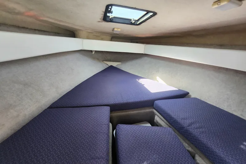Slide: The Image of 2017 Bayliner 210 Cuddy cabin interior with blue cushions and overhead hatch. - 19